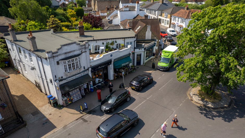 An alleyway scene with an overflowing pile of discarded cardboard boxes, black plastic bags, and assorted rubbish stacked against a weathered brick wall at the back. In the foreground, a large, beige,
